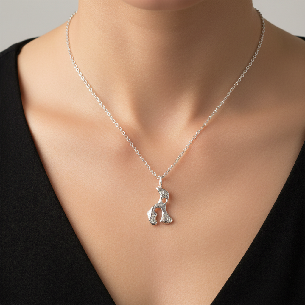 woman in a black v-neck top wearing a handmade sterling silver necklace in the shape of an elephant hippo rhino which is sustainable made in Nottingham by Bottlebee