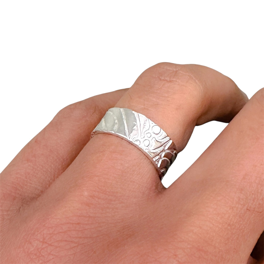 Solid sterling silver wedding ring with a textured design on a finger against a white background bespoke sustainable jewellery handmade in Nottingham by Bottlebee