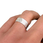Solid sterling silver wedding ring with a textured design on a finger against a white background bespoke sustainable jewellery handmade in Nottingham by Bottlebee
