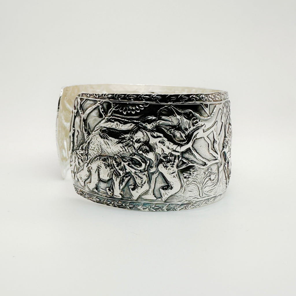 Silver cuff bracelet with intricate designs of elephants and giraffes on a white background made in Nottingham