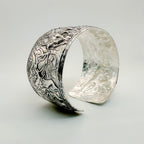 Silver cuff for man or woman with intricate animal design on a light background with giraffe and elephant