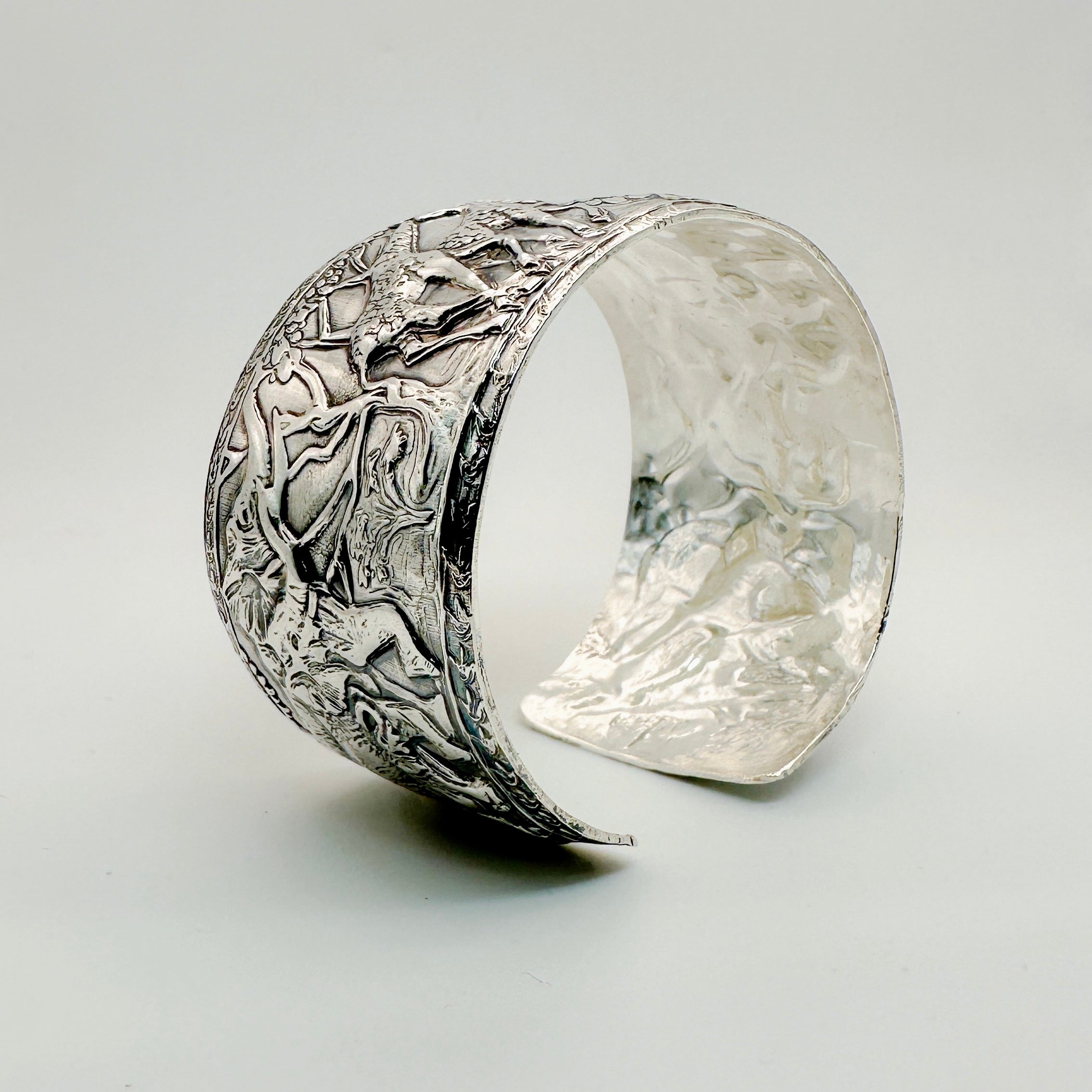 Silver cuff for man or woman with intricate animal design on a light background with giraffe and elephant