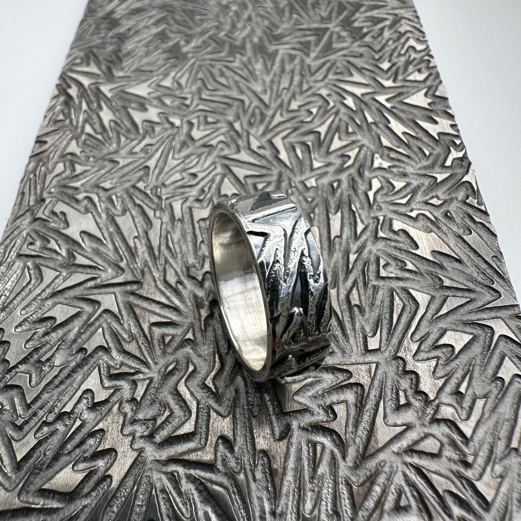 925 silver wedding ring band for a man woman or unisex with textured surface on a pattern plate used to make the design handmade sustainable bespoke jewellery Nottingham