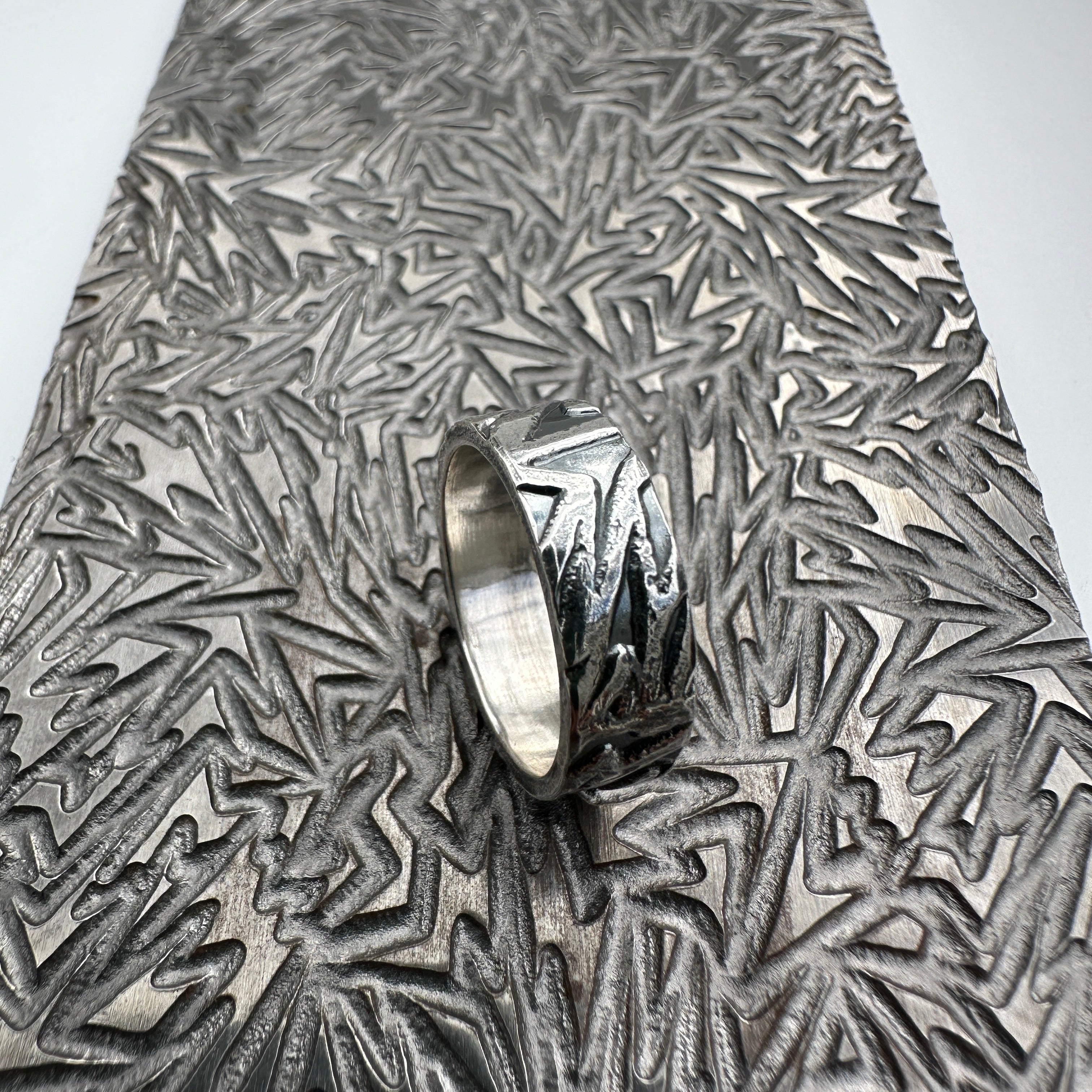 925 silver wedding ring band for a man woman or unisex with textured surface on a pattern plate used to make the design handmade sustainable bespoke jewellery Nottingham