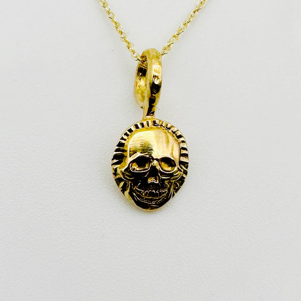 Gold skull pendant necklace on a light background