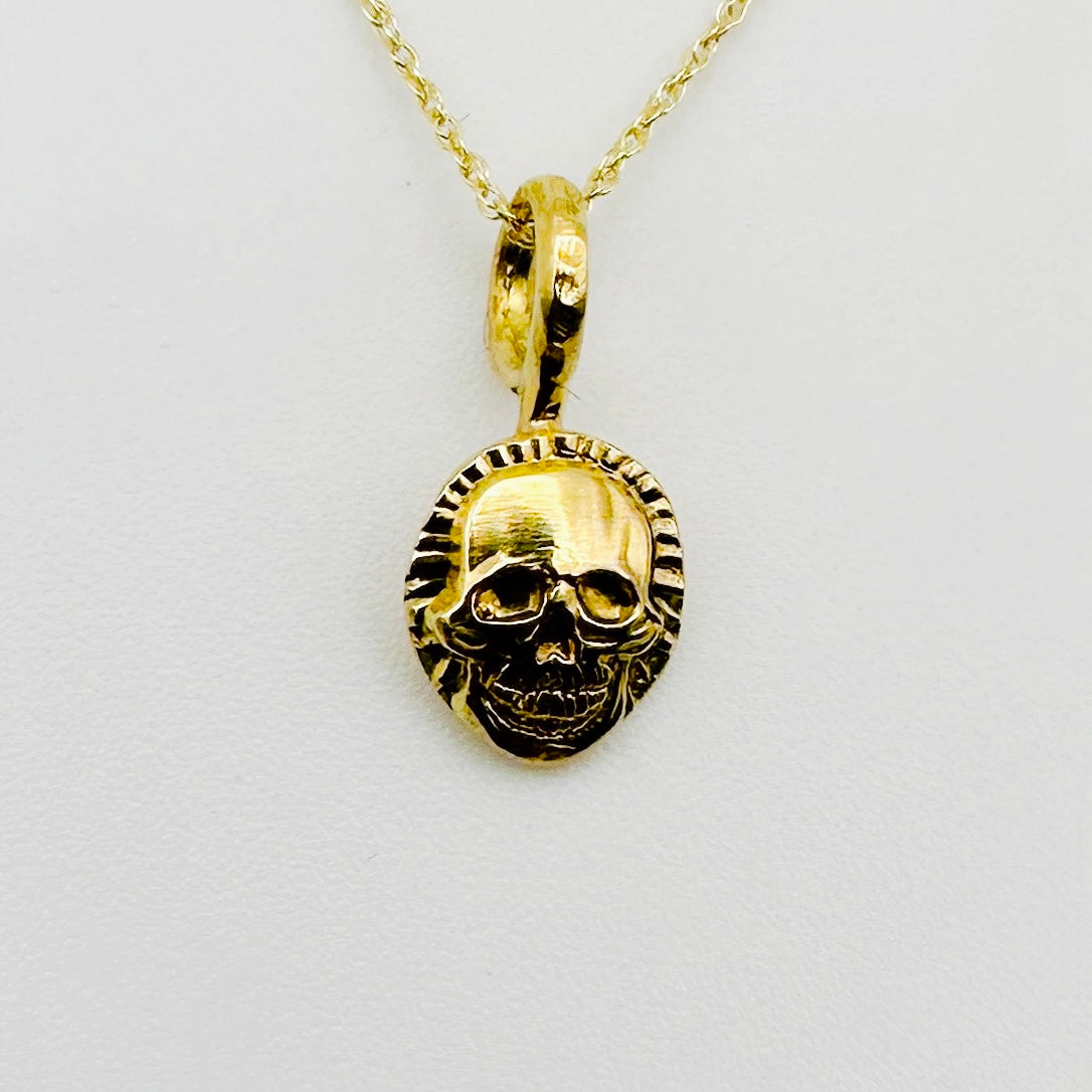 Gold skull pendant necklace on a light background