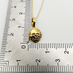 Gold skull pendant on a chain with a ruler for scale on a white background, jewellery handmade by Bottlebee in Nottingnam