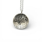 Silver necklace with a round pendant with thistles and flowers on a white background, handmade jewellery made by Bottlebee in Nottingham