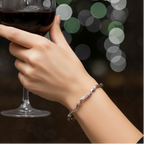 Textured and oxidised sterling silver bangle with wavy design on a womans arm holding a glass of red wine
