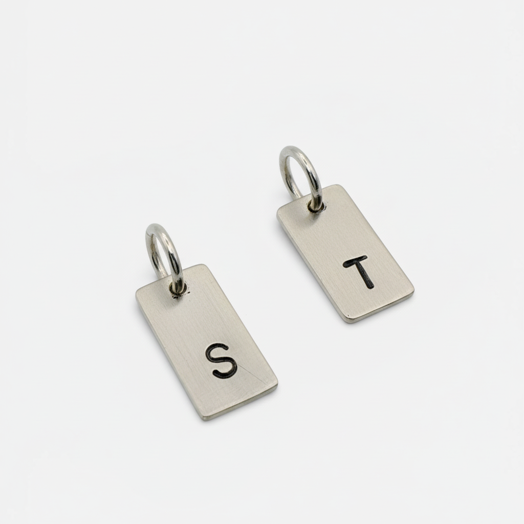 2 keyring tags made from sustainable sterling silver and hand stamped with an S and a T