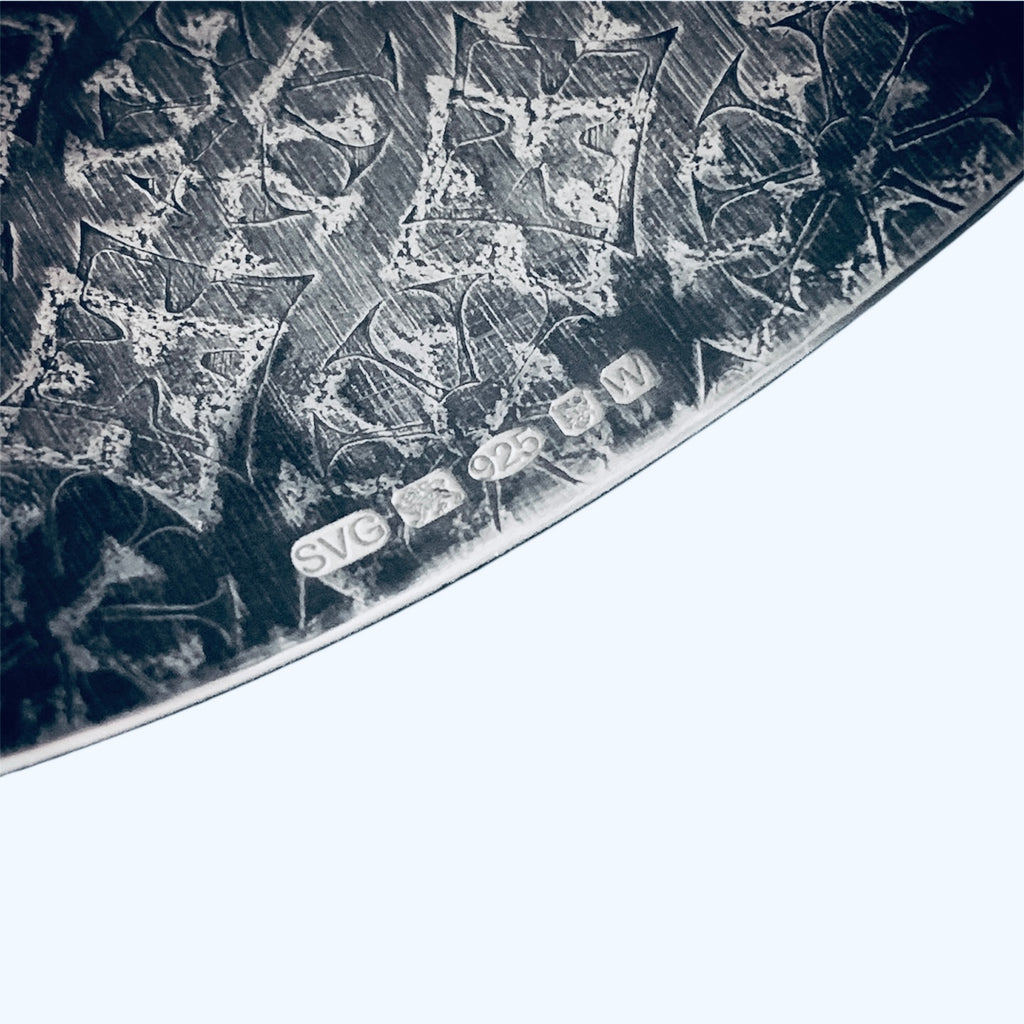 Close-up of a handmade bespoke cuff with art deco patterns and hallmark on white background made buy a small business based in Nottingham